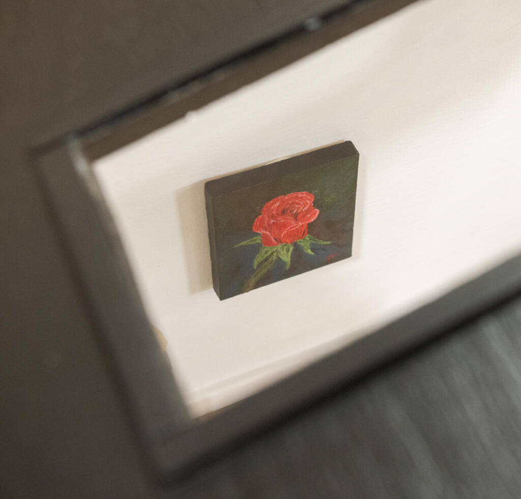 A tiny but incredibly detailed rose painting by Jan Patricio hangs on a wall inside the miniature Gallery 408 on Wednesday at Gallery 408 in Camas. The mini-gallery, which currently displays works by eight artists as well as by miniaturist and mini-gallery curator Lara Blair, will become a destination on the Worldwide Sidewalk Joy Project map, which tracks miniature art installations around the world. (Taylor Balkom/The Columbian)