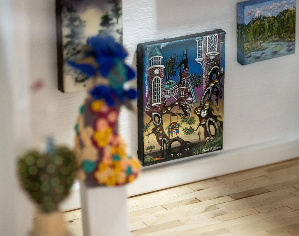Artwork by Chuck Bloom and other artists hangs on the walls of a miniature gallery. (Taylor Balkom/The Columbian)