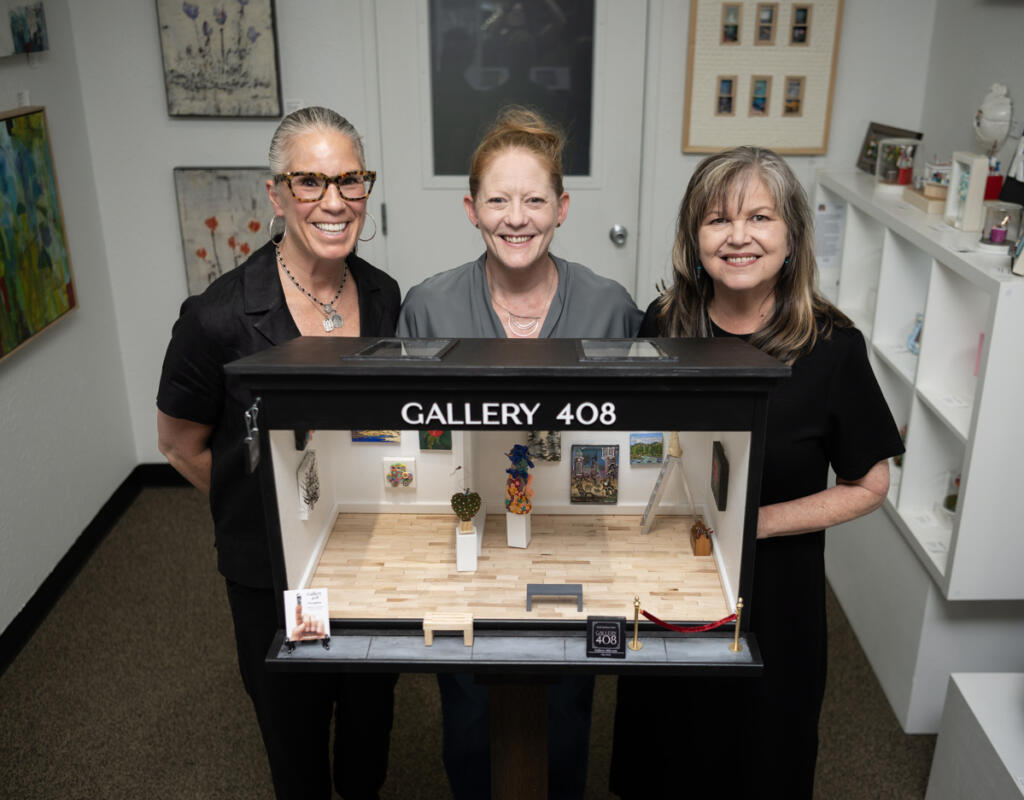 Curator and designer Lara Blair, from left, and Gallery 408 co-owners Michelle Purvis and Kim Nickens stand behind their new miniature gallery at Gallery 408 in Camas. The mini-gallery, which is having an official ribbon-cutting ceremony on June 5, will become part of the Worldwide Sidewalk Joy Project, which celebrates miniature art installations around the world. (Taylor Balkom/The Columbian)