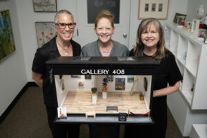 Curator and designer Lara Blair, from left, and Gallery 408 co-owners Michelle Purvis and Kim Nickens stand behind their new miniature gallery at Gallery 408 in Camas. The mini-gallery, which is having an official ribbon-cutting ceremony on June 5, will become part of the Worldwide Sidewalk Joy Project, which celebrates miniature art installations around the world. (Taylor Balkom/The Columbian)