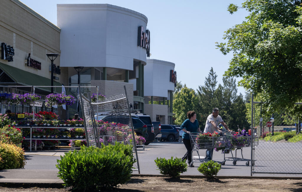 Customers pick up fresh flowers at the Fred Meyer in Salmon Creek on Monday morning. Inflation this summer may impact local families&rsquo; plans, such as traveling, sporting events and gardening.  At top, a sign advertises gas prices near the Fred Meyer in Salmon Creek on Monday. (Photos by Amanda Cowan/The Columbian)