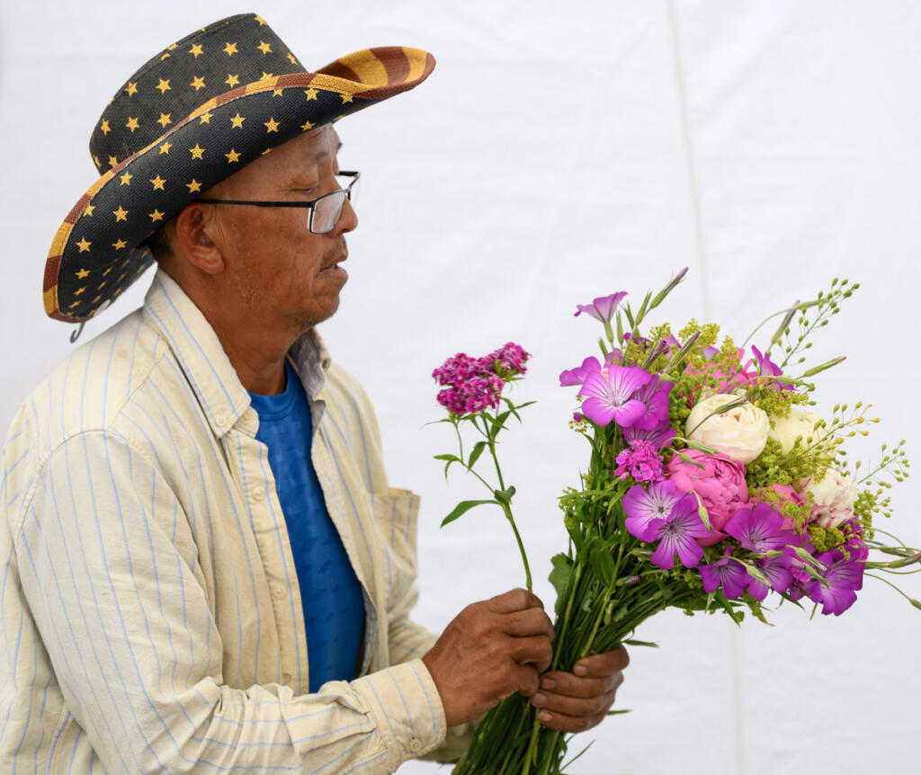 Richard Xiong arranges a bouquet June 3 at the Xiong Flower Farm booth at the Camas Farmers Market. &ldquo;We&rsquo;re so excited, even with the new location,&rdquo; said Leah Nichelson, the market&rsquo;s manager and vendor liaison. (Taylor Balkom/The Columbian)