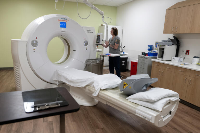 CT technician Kelly Chavez prepares the room for a patient while working at Vancouver Clinic&rsquo;s Salmon Creek Urgent Care facility June 4.