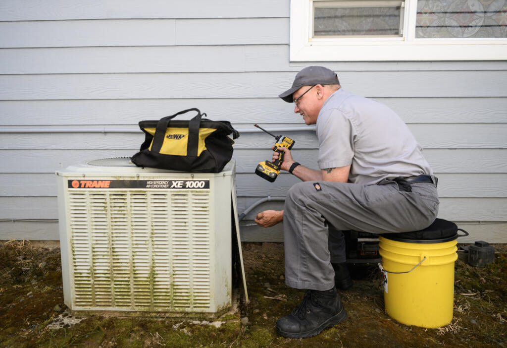 All Seasons Heating and Cooling service manager Ken Sullivan works on an air conditioning unit Friday in Camas. (Photos by Taylor Balkom/The Columbian)