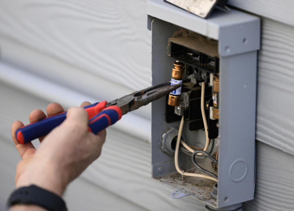 Ken Sullivan installs a new fuse Friday in Camas. (Taylor Balkom/The Columbian)