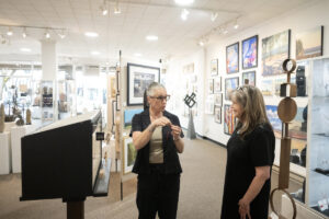 Curator Lara Blair, center, and gallery owner Kim Nickens chat May 27 next to a miniature Gallery 408 installation in Camas. Gallery 408 has been accepted into the Seattle Art Fair, which will be held in July. (Taylor Balkom/The Columbian)