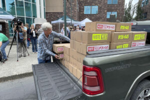 A volunteer for Let&rsquo;s Go Washington unloads boxes of petitions for Initiative 645 that were turned in to the secretary of state&rsquo;s office on July 2. The measure to repeal Washington&rsquo;s new income tax was certified for the November ballot on July 15. (Jerry Cornfield / Washington State Standard)