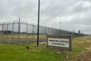 A sign and fence at the Green Hill School for juvenile offenders, in Chehalis, Washington. (Photo by Jake Goldstein-Street/Washington State Standard)