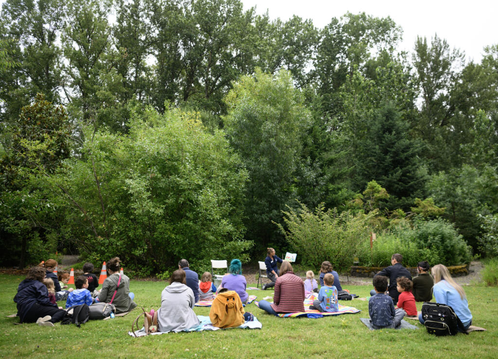 Kids and adults sit on blankets and listen to a story read by educator Erin Bowen on Wednesday during a Reading in the Wild event at the Water Resources Education Center in Vancouver. (Photos by Taylor Balkom/The Columbian)