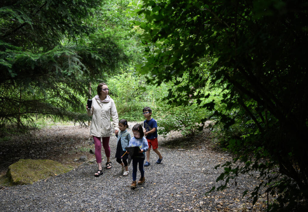 Royce Andrews, from left, walks with her kids Penelope Eakin, 4, Cora Eakin, 4, and Atlas Eakin, 5, during a scavenger hunt July 1 during a Reading in the Wild event at the Water Resources Education Center in Vancouver. (Photos by Taylor Balkom/The Columbian)