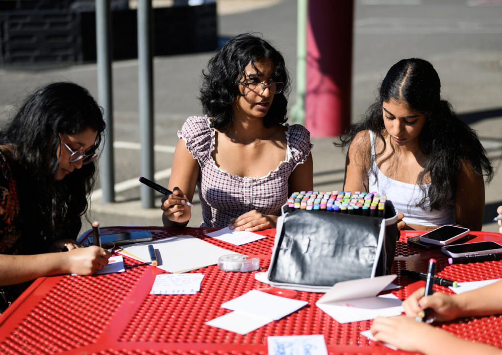 Comfort4Cancer founder Roshni Madugula, 15, center, talks with others, including her sister Tanya, 13, right, and Srijani Gireddy, 17, while the group makes cards for cancer patients Friday at Prune Hill Sports Park in Camas. (Taylor Balkom/The Columbian)