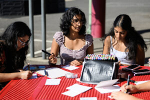 Comfort4Cancer founder Roshni Madugula, 15, center, talks with others, including her sister Tanya, 13, right, and Srijani Gireddy, 17, while the group makes cards for cancer patients Friday at Prune Hill Sports Park in Camas. (Taylor Balkom/The Columbian)