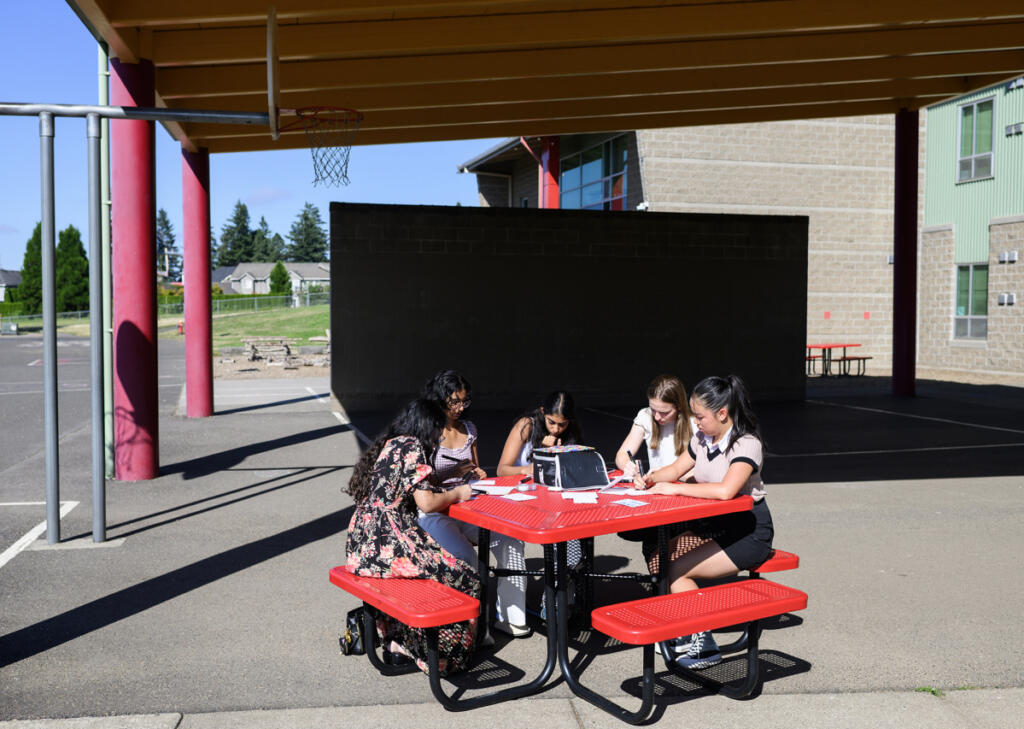 Srijani Gireddy, 17, clockwise from left, Comfort4Cancer founder Roshni Madugula, 15, Tanya Madugula, 13, Brittan Fine, 15, and Abigail Lim, 15, all work on cards for cancer patients Friday at Prune Hill Sports Park in Camas. (Taylor Balkom/The Columbian)