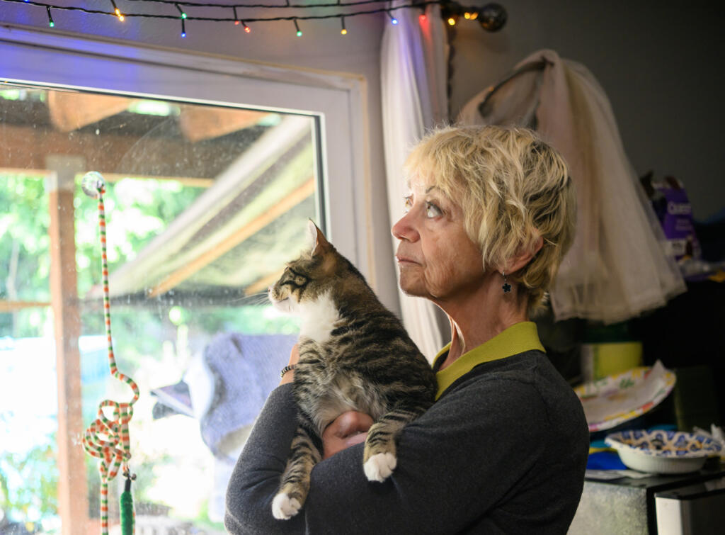 Home care aide Vicki Bickford looks at string lights while holding her cat Pippin at Bickford&rsquo;s home in Vancouver. (Taylor Balkom/The Columbian)