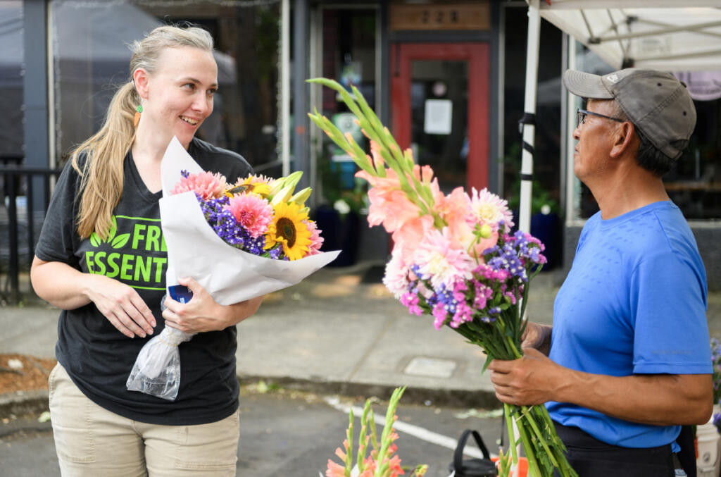 Camas Farmers Market Manager Leah Nichelson, left, chats with florist Richard Xiong of Xiong Flower Farm on July 22 at the Camas Farmers Market. Nichelson will become the new Downtown Camas Association executive director after current director Carrie Schulstad steps down later this year. (Photos by Taylor Balkom/The Columbian)