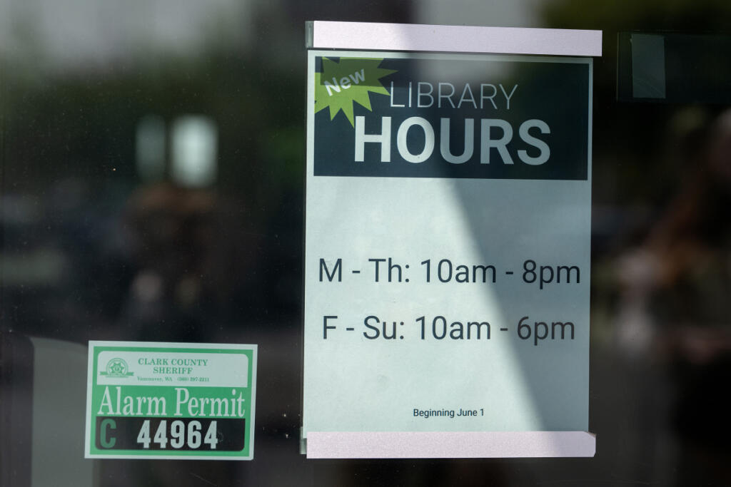 A sign in the window of Three Creeks Community Library notifies the public of new hours on Tuesday morning. (Amanda Cowan/The Columbian)