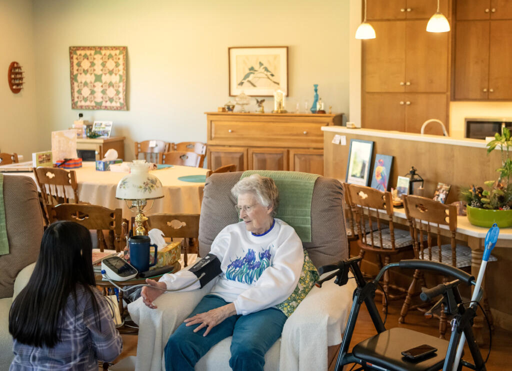 Home Instead caregiver Andrea Salinas, left, checks client Betty Tribe&rsquo;s vital signs on July 30 at Tribe&rsquo;s home in Ridgefield. (Photos by Taylor Balkom/The Columbian)