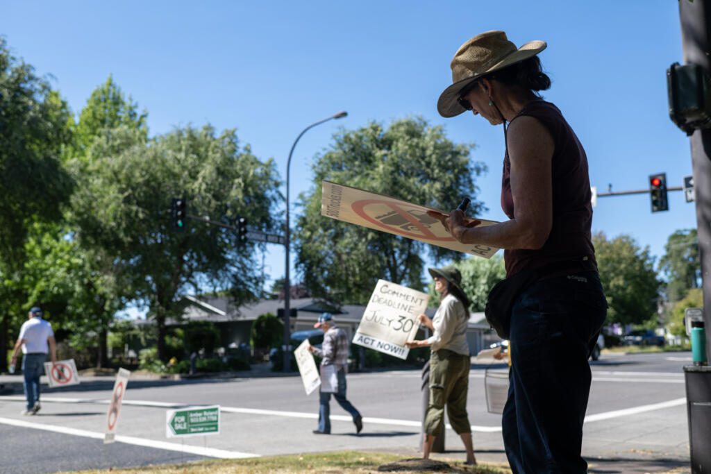 Megan Light of Washougal, right, helps create protest signs while joining fellow demonstrators in downtown Washougal on Friday. J.L. Storedahl & Sons submitted an application to open a gravel mine north of Washougal, raising concerns about traffic and impacts to the Columbia River Gorge.