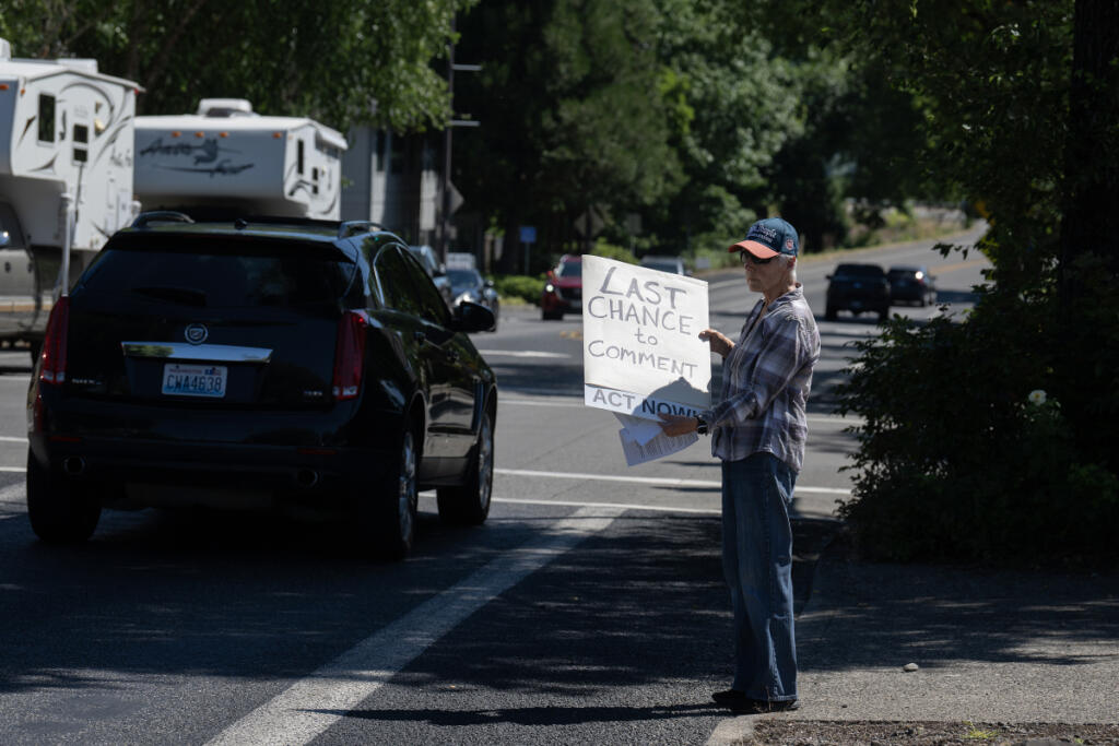 Skamania County resident Roberta Doster greets motorists during a Friday protest in Washougal. J.L. Storedahl & Sons submitted an application to open a gravel mine north of Washougal, raising concerns about traffic and impacts to the Columbia River Gorge. (Amanda Cowan/The Columbian)