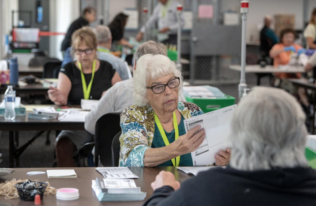 Brinda Wood of Vancouver, cq, center, inspects ballots at the Clark County Elections Office on Monday morning, Aug. 3, 2026. (Amanda Cowan/The Columbian)