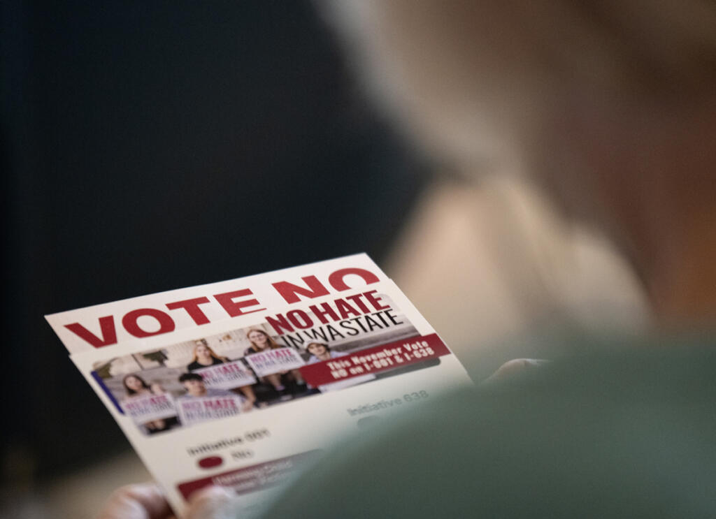 A rally attendee reads pamphlets Aug. 14 during a No Hate in WA State rally at Fourth Plain Community Commons in Vancouver. The rally was in opposition to two conservative state ballot initiatives, I-001 and I-638. (Photos by taylor balkom/The Columbian)