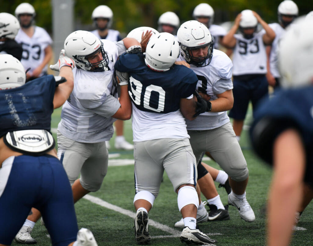 Skyview lineman Lucas Wiggins, left, and Howard Lester, right, block Jabari Bickham (90). The Storm will open its season at Glacier Peak in Snohomish. (Tim Martinez/The Columbian)