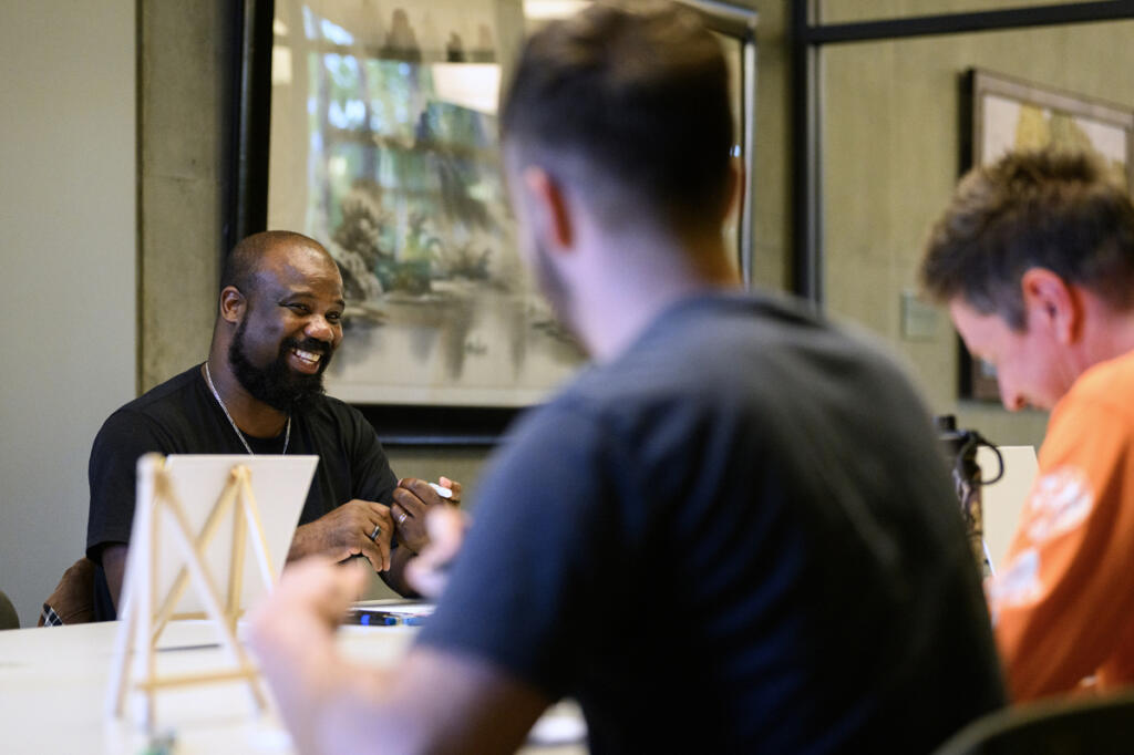 Gentle Strength Project leader David Bradley, left, laughs Sept. 3 during a Gentle Strength Project paint night at Vancouver Community Library. (Taylor Balkom/The Columbian)