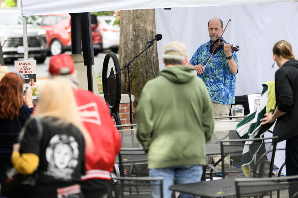 Seth Moran, right, plays a fiddle as people walk down Northeast Fourth Avenue on Sept. 4 during First Friday in downtown Camas. (Taylor Balkom/The Columbian)