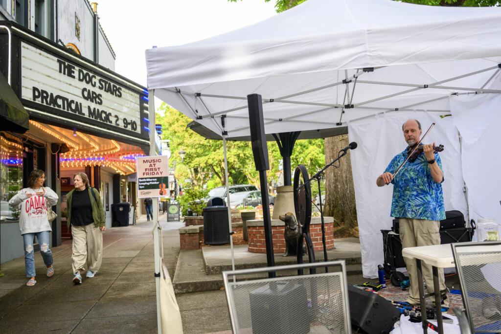 Seth Moran, right, plays a fiddle as people walk down Northeast Fourth Avenue Sept. 4 during First Friday in downtown Camas. (photos by Taylor Balkom/The Columbian)