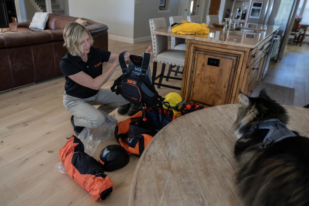 Susan Anderson, senior director of disaster response for the American Society for the Prevention of Cruelty to Animals, looks over some of the gear she uses in the field while relaxing at her Vancouver home with her kitty, Bronto, 10, on Sept. 16. Anderson has deployed to countless natural disasters to help reunite displaced pets with their families and support animals left behind or in need of relocation. (Photos by Amanda Cowan/The Columbian)