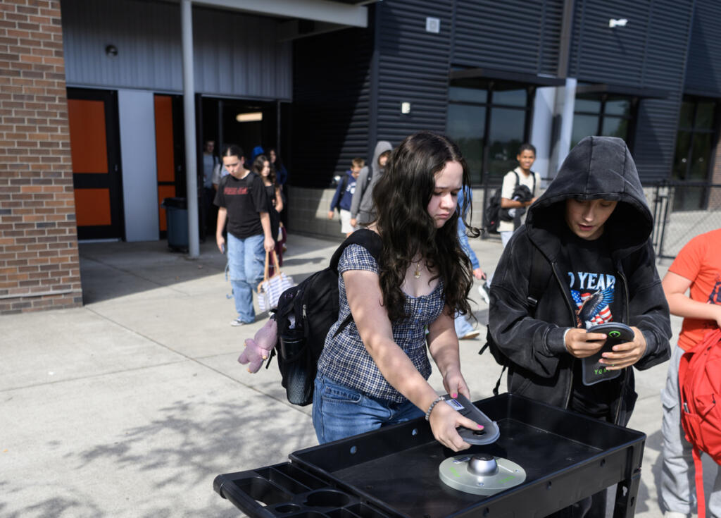 Seventh grader Elanor McCain, left, and sixth grader Tucker Koch unlock their Yondr device pouches after classes Monday at View Ridge Middle School. The Ridgefield School District implemented an &ldquo;away for the day&rdquo; cellphone policy a year ago. (Photos by Taylor Balkom/The Columbian)