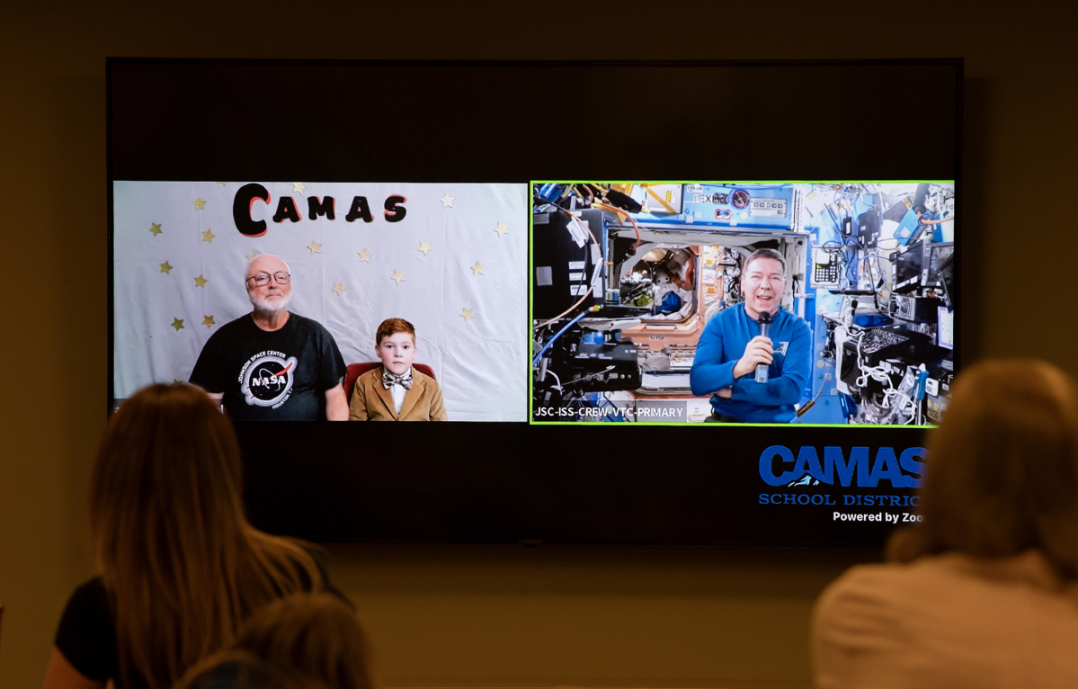 Earthbound former science teacher Dale Croswell, left, and student Miles Nichols chat from Camas with astronaut Dr. Michael Barratt as he travels aboard the International Space Station in May 2024. (The Columbian files)