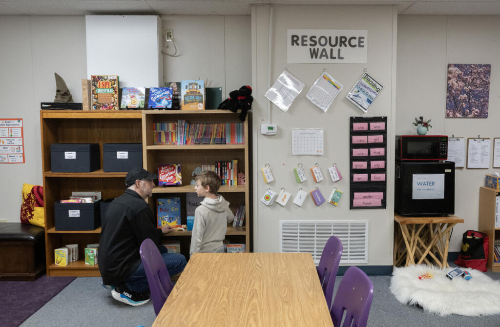 Reading mentor Lee Campen, left, helps third grader Kellin Bartholomew, 8, select a book during a Read Northwest session Dec. 8 at Hathaway Elementary School. The school has been identified as a primary candidate to be closed. (Amanda Cowan/The Columbian file photos)