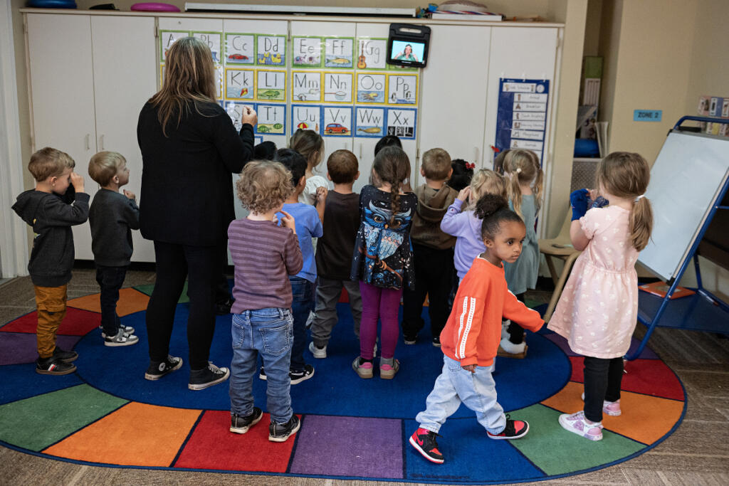 Milah Collins, 4, in orange, joins fellow students during the wiggle dance at the Battle Ground Early Learning Center on Monday morning. In August, the Trump administration proposed an overhaul of Head Start that would eliminate most of the federal early childhood program&rsquo;s regulations.  At top, a child reaches out for help with pouring a glass of milk during lunchtime at the Battle Ground Early Learning Center. (Photos by Amanda Cowan/The Columbian)