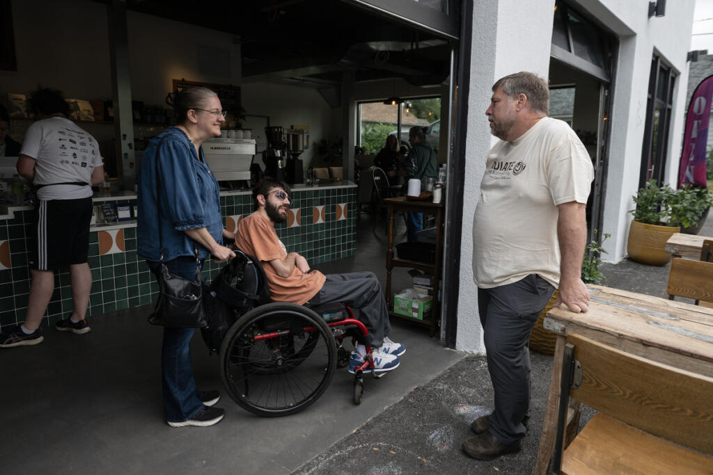Jerrilynn Coblentz of Vancouver, left, brings her son, Caleb Coblentz, 26, to work at Radiate Coffee and Community. Caleb Coblentz offers IT support, said the coffee shop&rsquo;s owner, David Wigen, right. (Amanda Cowan/The Columbian)