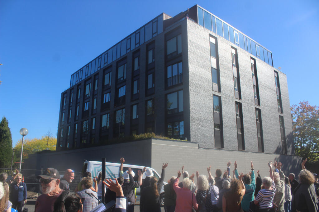 Attendees wave to a photographer, taking a photo from the top floor of the Walden Apartments complex, during Thursday&rsquo;s groundbreaking ceremony for FVRLibraries&rsquo; new Washougal library. (Doug Flanagan/The Columbian)