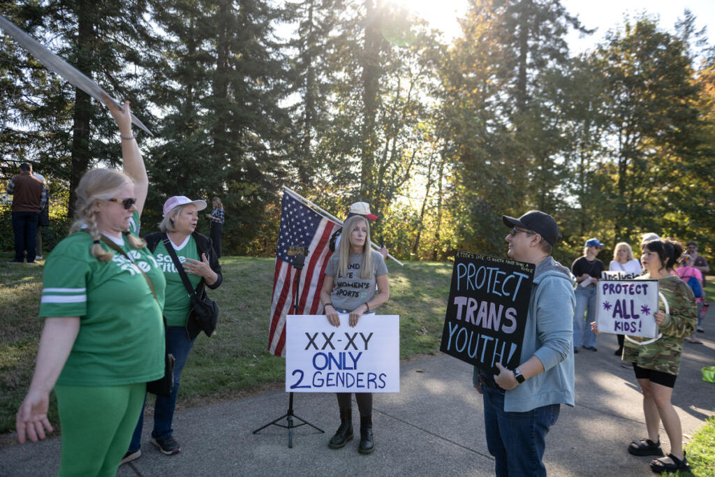 Demonstrators with opposite points of view face each other outside Wednesday&rsquo;s 4A Greater St. Helens League district cross country championship in Camas, where a transgender girl competed. (Amanda Cowan/The Columbian)